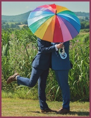 Happy couple underneath a rainbow umbrella