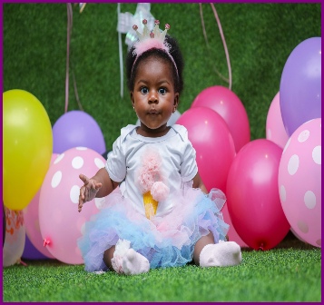 Little girl in princess outfit amongst balloons