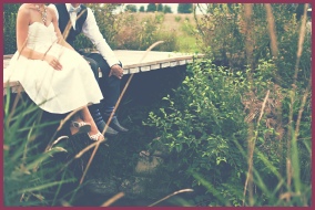 Romantic couple sat on a wooden bridge
